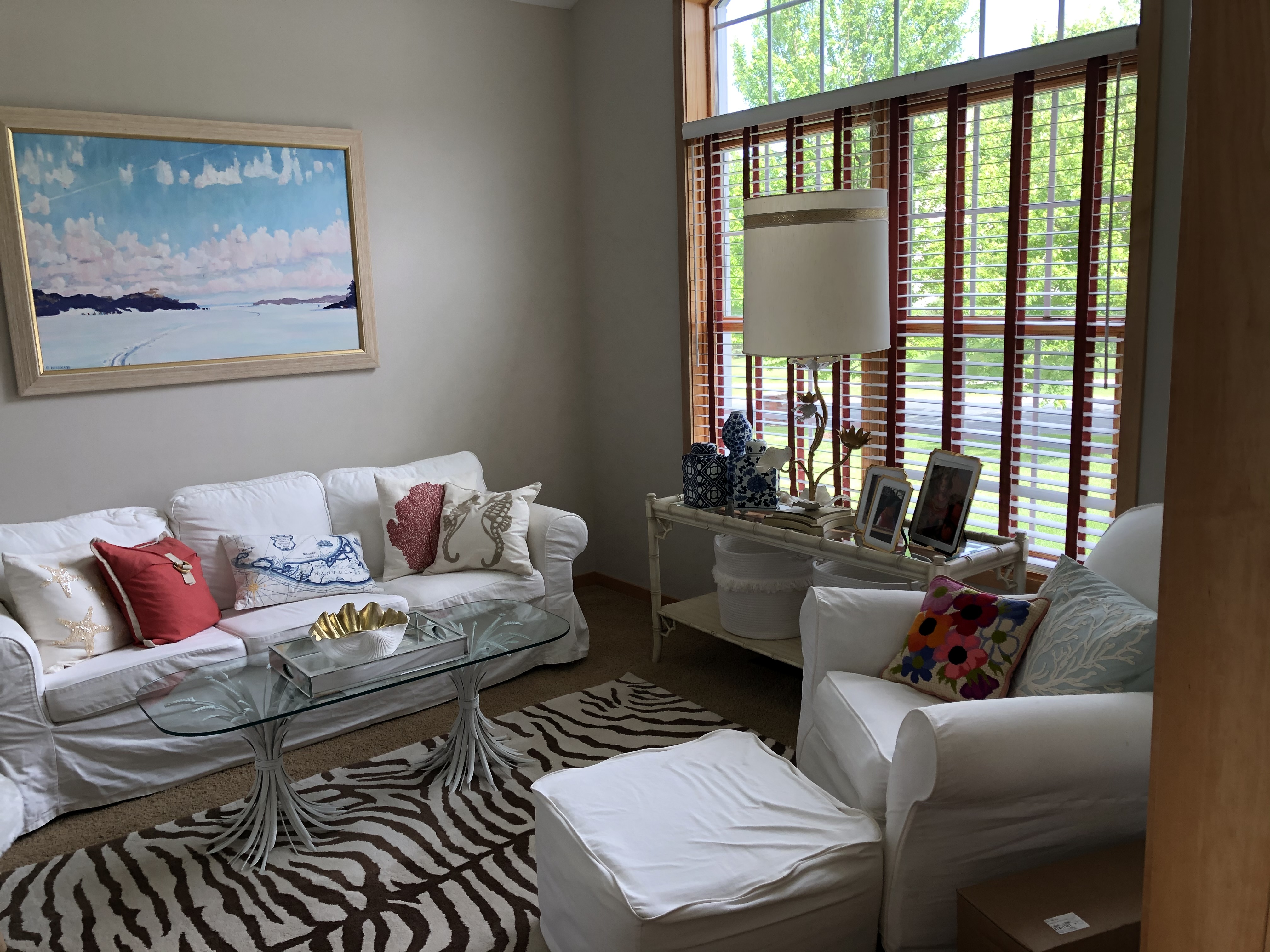 Living room with zebra rug, white slipcovered sofa, and coastal art